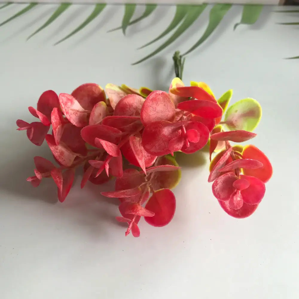 A cluster of decorbites artificial ferns shrubs with red and yellow glossy plastic eucalyptus leaves for living room decor