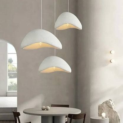 Three matte gray shell-shaped led wabi sabi chandelier pendant lights hanging in a dining room setting