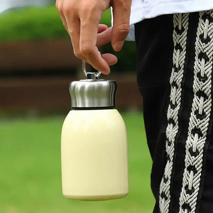 Cream-colored stainless steel vacuum flask with silver lid and carrying loop for travel water bottle use