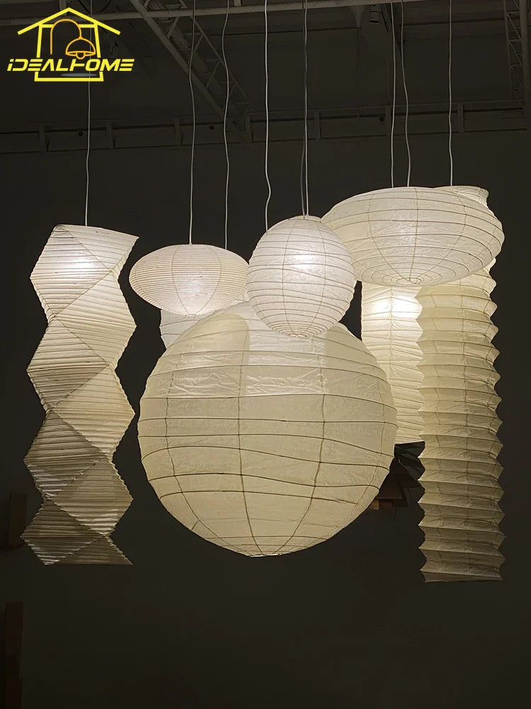 A collection of white akari noguchi yong pendant lights made of rice paper with spherical and twisted designs suspended from ceiling