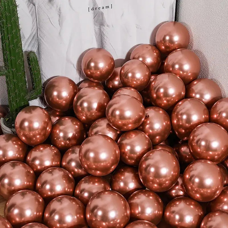 A pile of rose gold metallic chrome golden balloons with a shiny reflective surface for wedding party decor