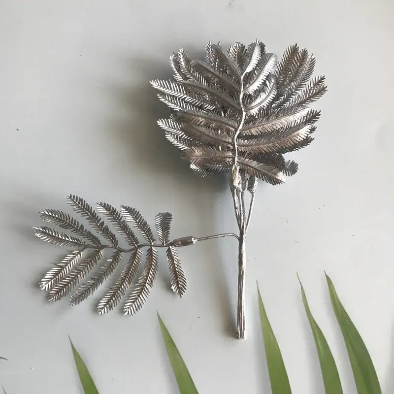 Metallic silver eucalyptus leaf wall decor with intricate detailing and slender stem for living room display