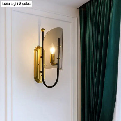 Gold-toned wall mount lamp with a curved black metal arm and smoke grey glass shade for hall wall lighting