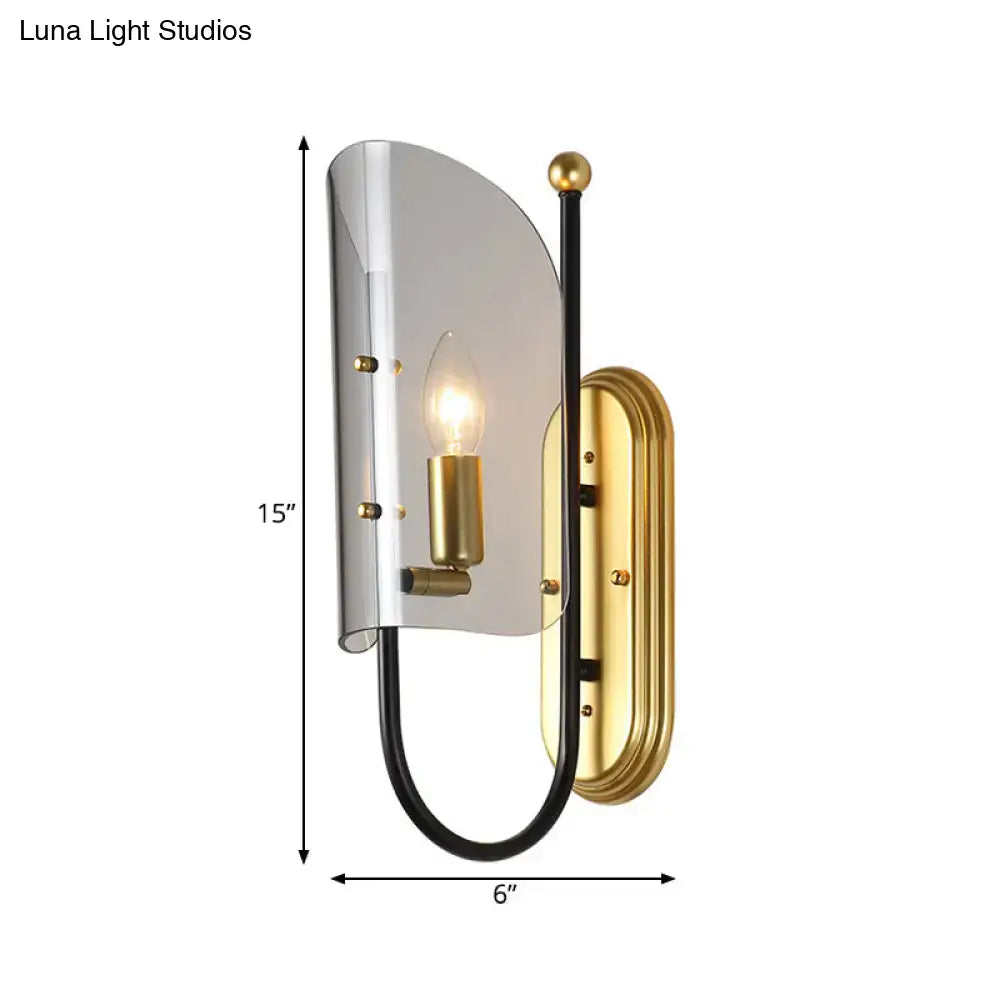 A mid century wall mount lamp with brushed brass, black metal arm, and smoke grey glass shade for hall wall lighting