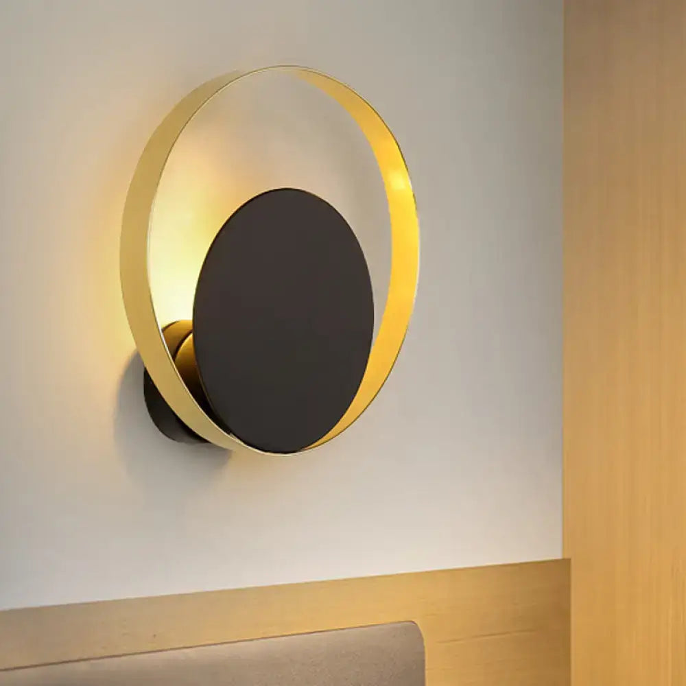 Mid century black and gold circle sconce featuring a modern gold-toned circular design with a matte black central disc