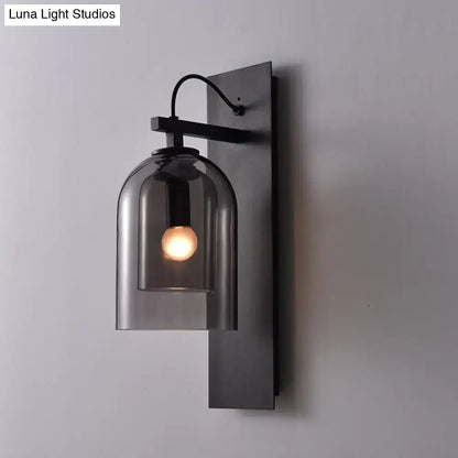 Black metal wall sconce with smoked dome glass shade and exposed bulb, mid-century style for living room use