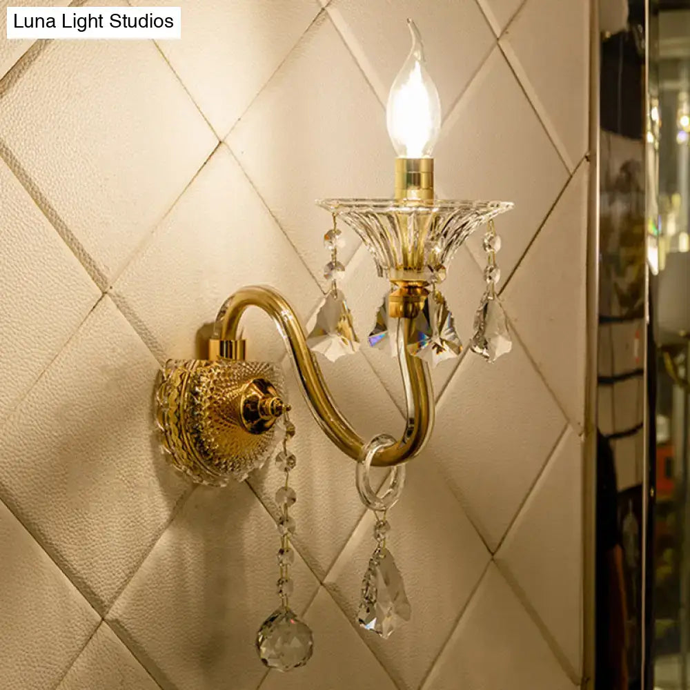 Mid-century brass wall mounted sconce with gold-toned crystal shade and lit candle-style lights wall fixture