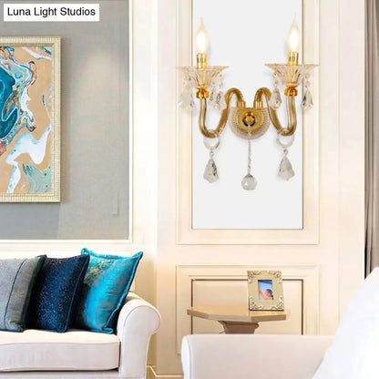 Mid-century brass crystal shade wall mounted sconce featuring gold-toned finish and two lit candle-style lights wall fixture