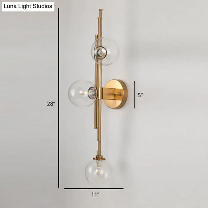 Mid century brass finish wall sconce with three clear glass orb shades and minimalist vertical fixture height design