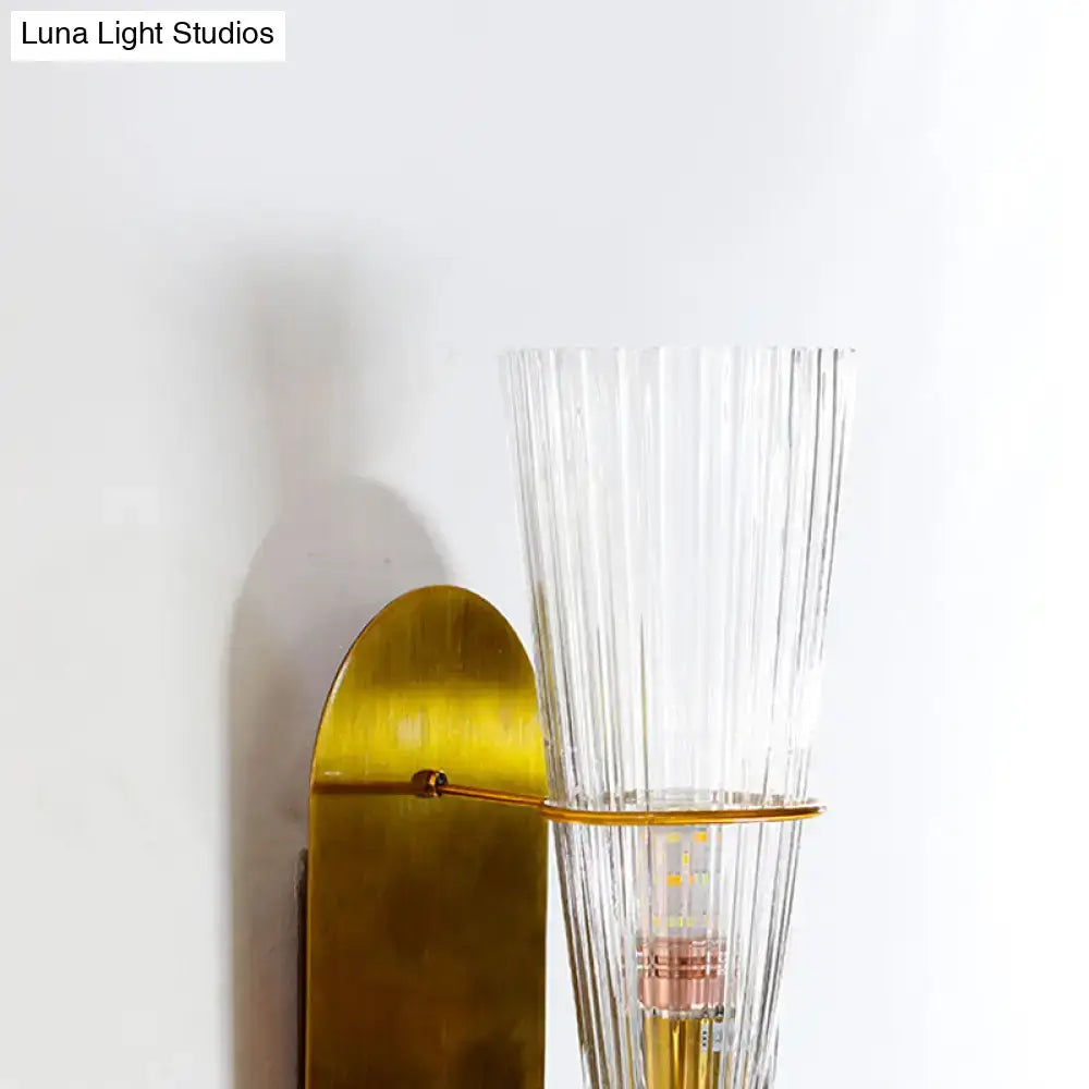 Mid century brass wall lamp with gold-toned finish and clear ribbed glass single light for bedroom use
