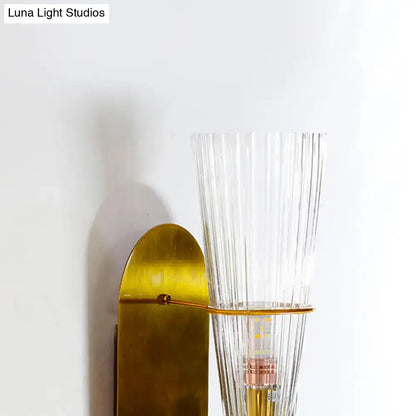 Mid century brass wall lamp with gold-toned finish and clear ribbed glass single light for bedroom use