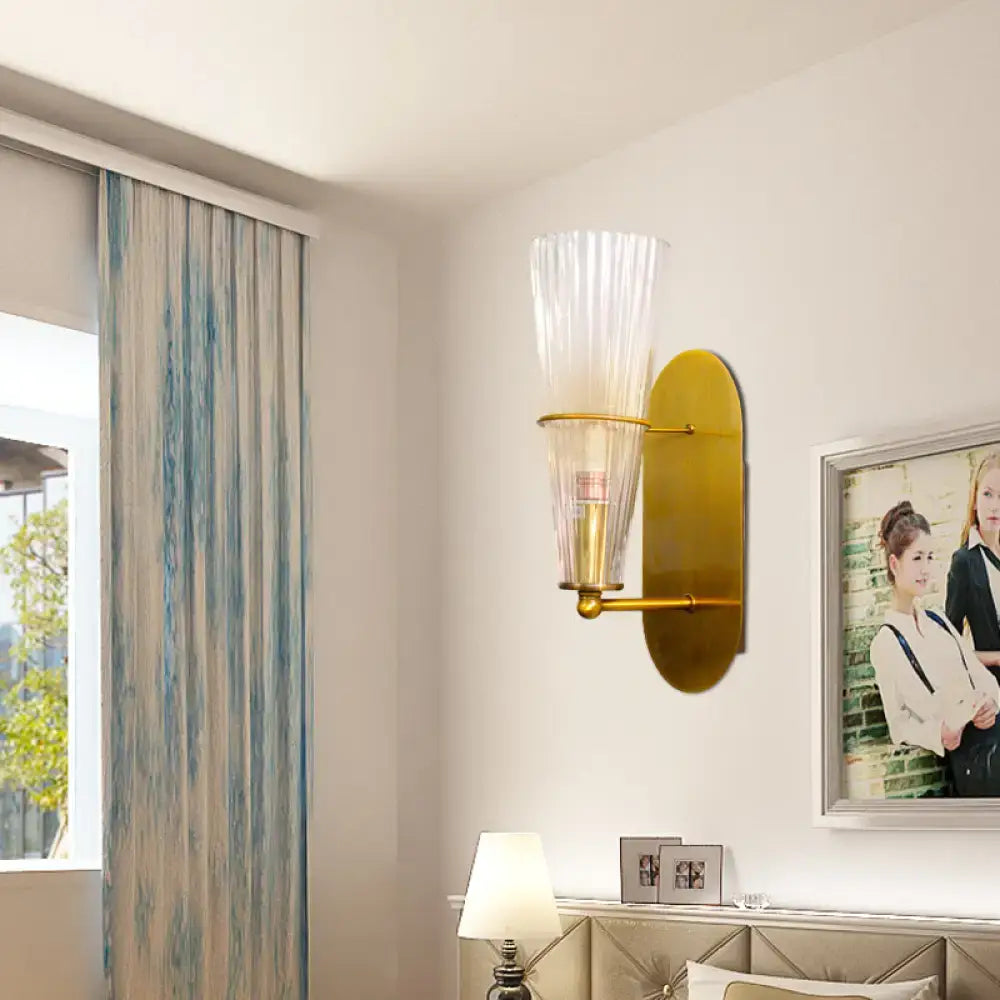 Mid century brass wall lamp with gold-toned finish and clear ribbed glass single light for bedroom use