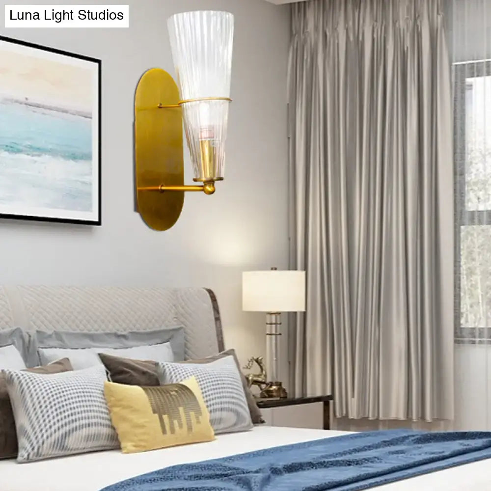 Mid century brass wall lamp with gold-toned finish and clear ribbed glass single light shade for bedroom use