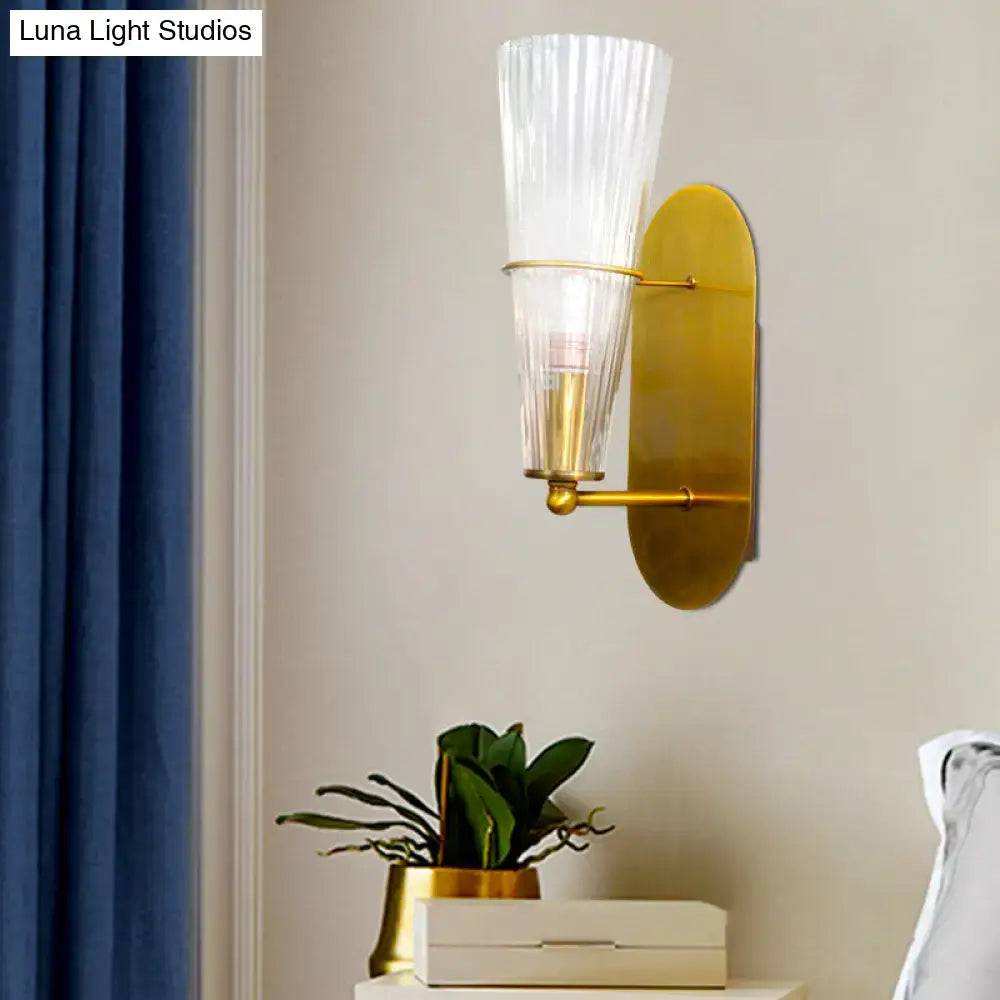 A sleek mid century brass wall lamp with clear ribbed glass single light and gold toned fluted translucent shade