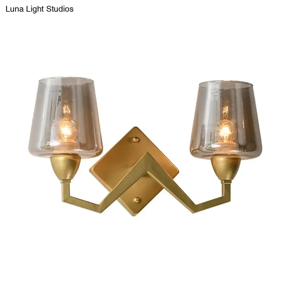Gold-toned mid-century brass wall lamp featuring a truncated cone shade with two smoked glass shades for bedroom use