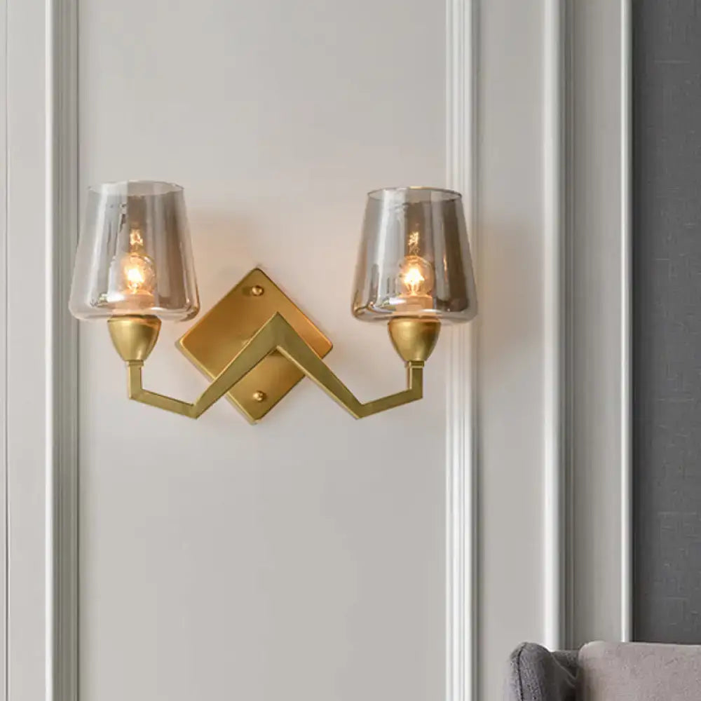 Gold-toned mid-century brass wall lamp with two frosted truncated cone shades and geometric angular design for bedroom