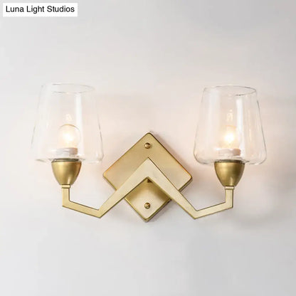 Gold-toned mid-century wall lamp with truncated cone shades and clear glass for bedroom lighting