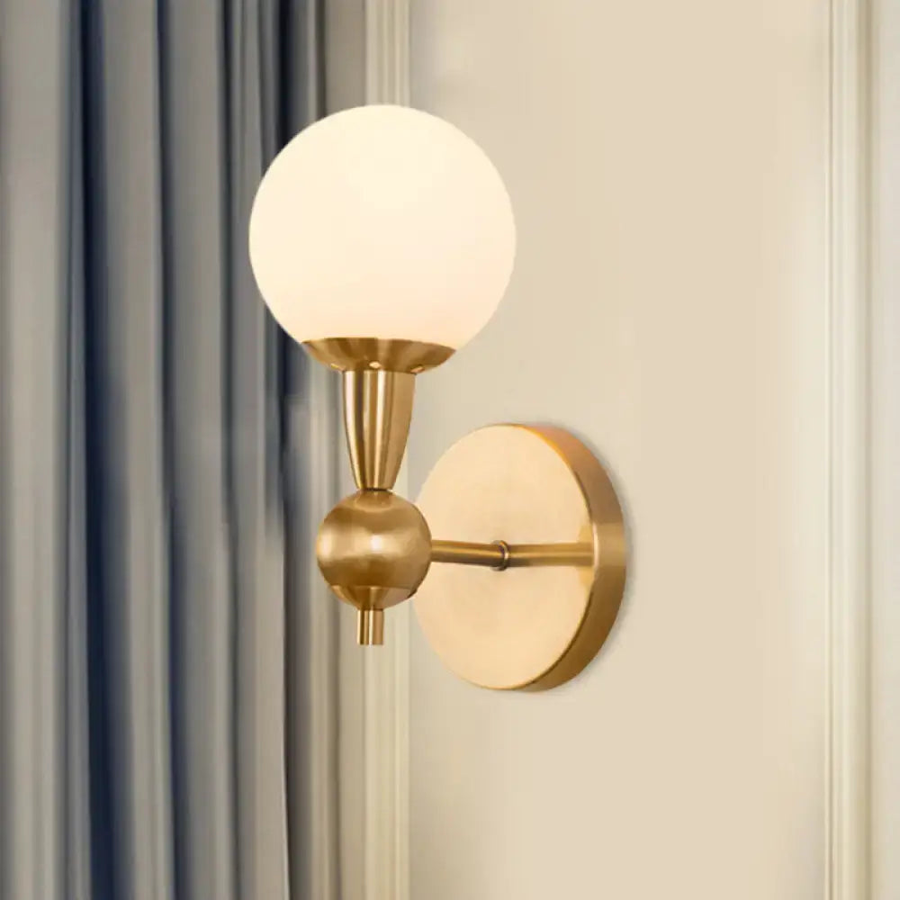 Mid century wall mount light with gold-toned brass finish and frosted opal glass globe for 220v-240v and 110v-120v use