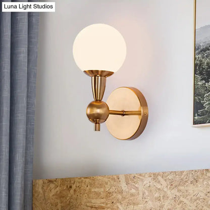 A sleek mid century wall mount light in brass with a frosted opal glass globe for bedroom 220v-240v 110v-120v use