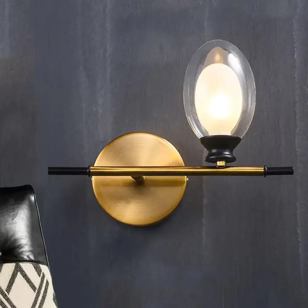 Mid century gold and black wall lamp with clear amber glass oval shade for bedroom lighting