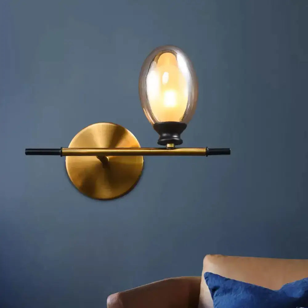 Mid century gold and black wall lamp with sleek horizontal bar and clear amber glass shade for bedroom lighting