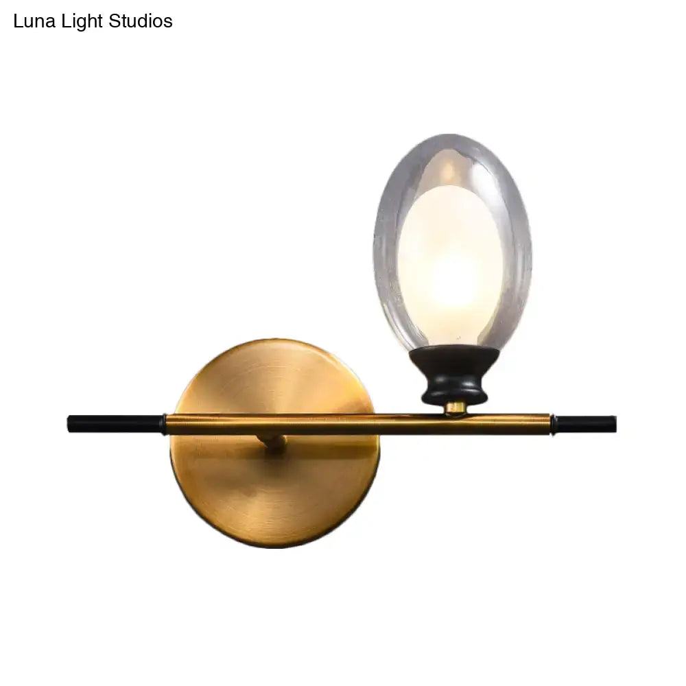 Mid century gold and black wall lamp with sleek black bar and oval clear amber glass shade for bedroom lighting