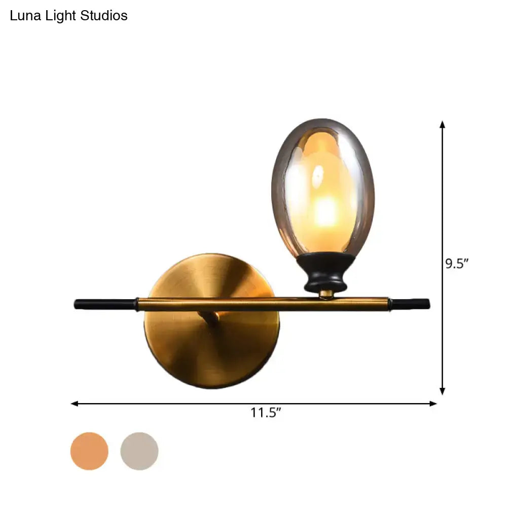 Mid century gold and black wall lamp with amber glass shade and sleek black rod for bedroom lighting