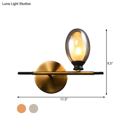 Mid century gold and black wall lamp with amber glass shade and sleek black rod for bedroom lighting