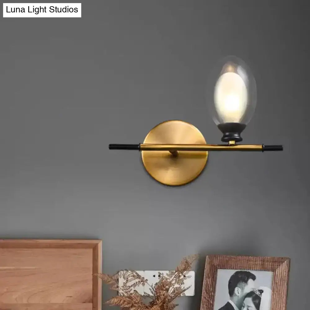 Mid century gold and black wall lamp with clear amber glass oval shade and sleek black horizontal bar