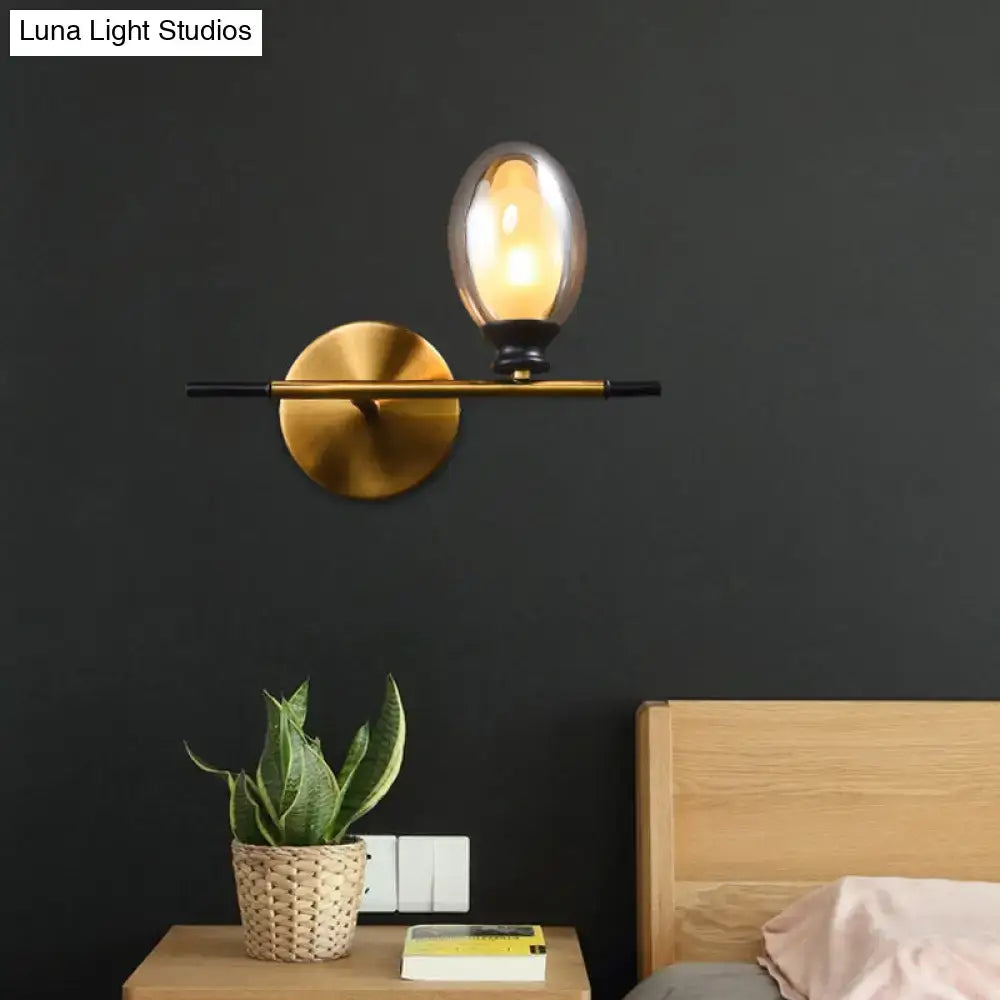 Brass-finished wall lamp with sleek black bar and oval smoked amber glass shade ideal for bedroom lighting