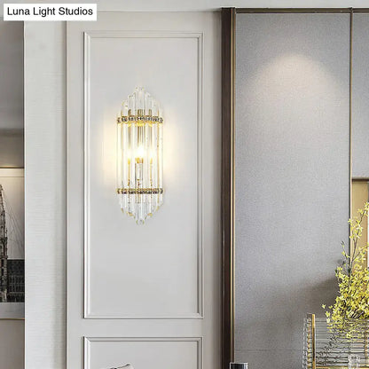 A mid century gold crystal pipe flush wall sconce with clear crystal prisms and warm glow for living room use