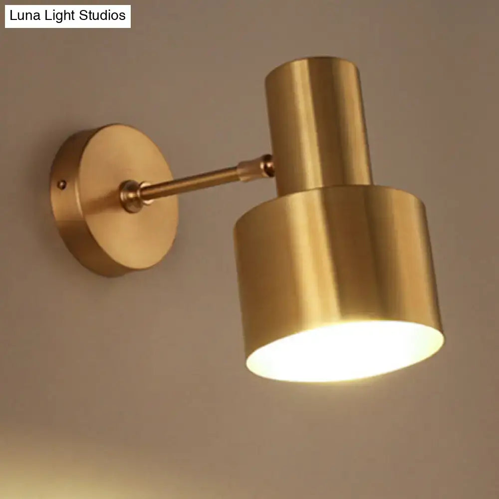 Brass-finished adjustable wall sconce with cylindrical shade and circular mount for stylish home wall lighting