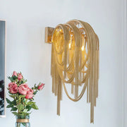 Gold-toned mid century wall lamp with silver stacked tassel chain fringe and rectangular backplate for bedroom sconce