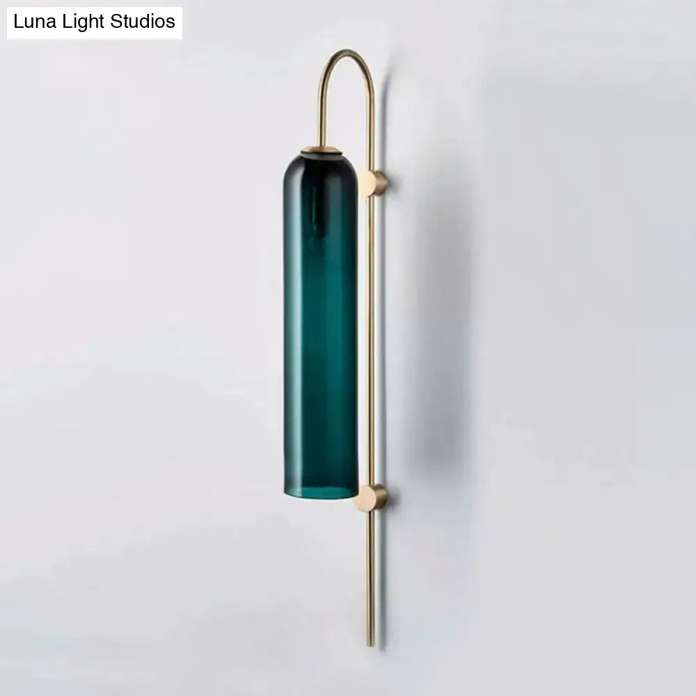 A mid century gooseneck wall light with a deep teal glass shade and slender brass frame for bedroom use