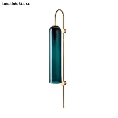 A mid century gooseneck wall light with a teal glass cylinder and brass arm for bedroom sconce lighting