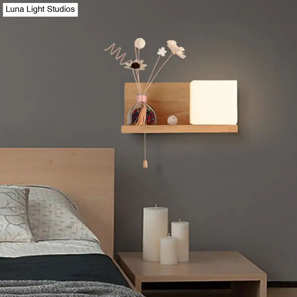 Minimalist wooden wall shelf with a white milk glass cube wall light and dried flowers in a glass vase bedroom sconce