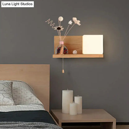 Minimalist wooden wall shelf with a white milk glass cube wall light and dried flowers in a glass vase bedroom sconce