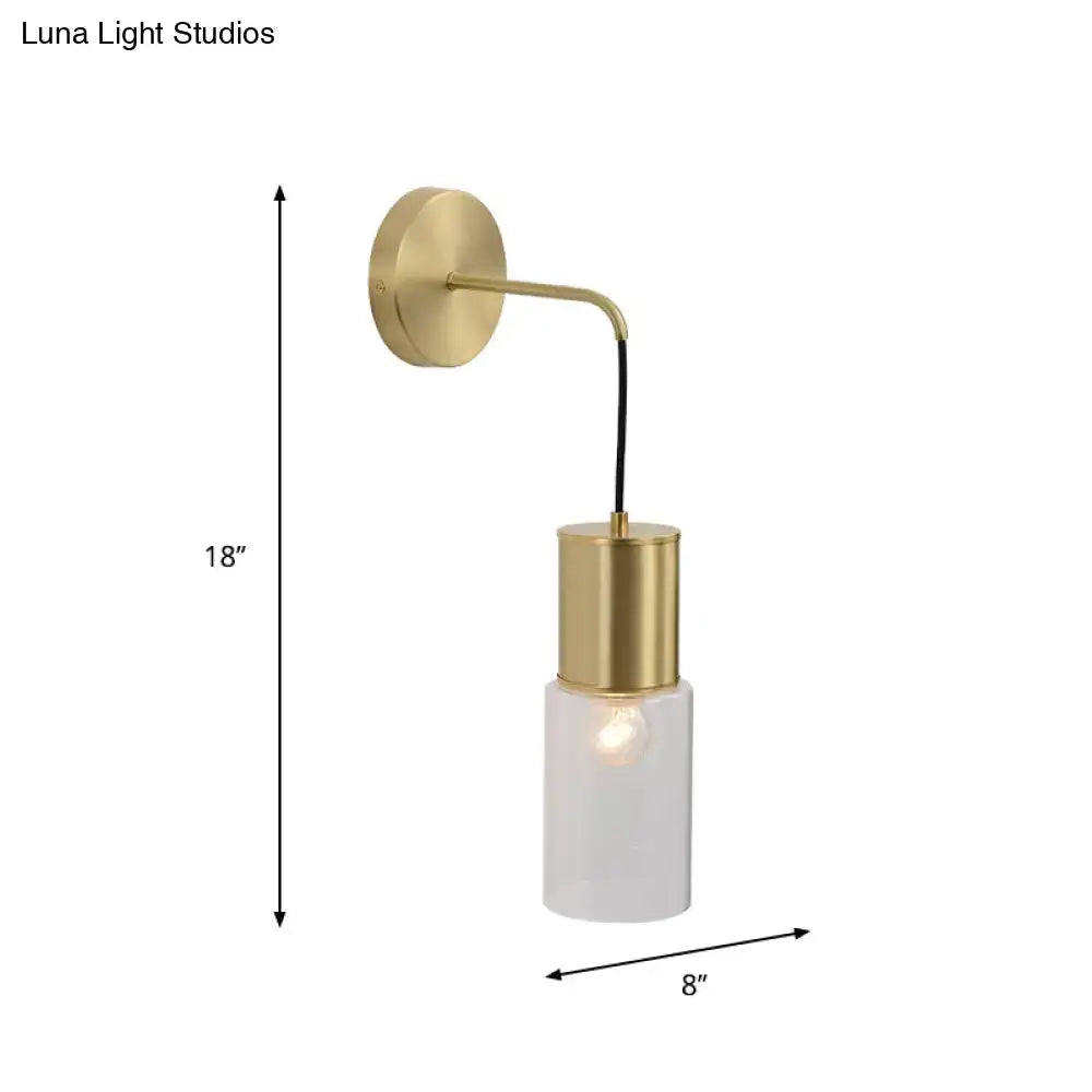Minimal brass and glass wall sconce light with gold-toned curved arm and frosted glass cylinder for bedroom use