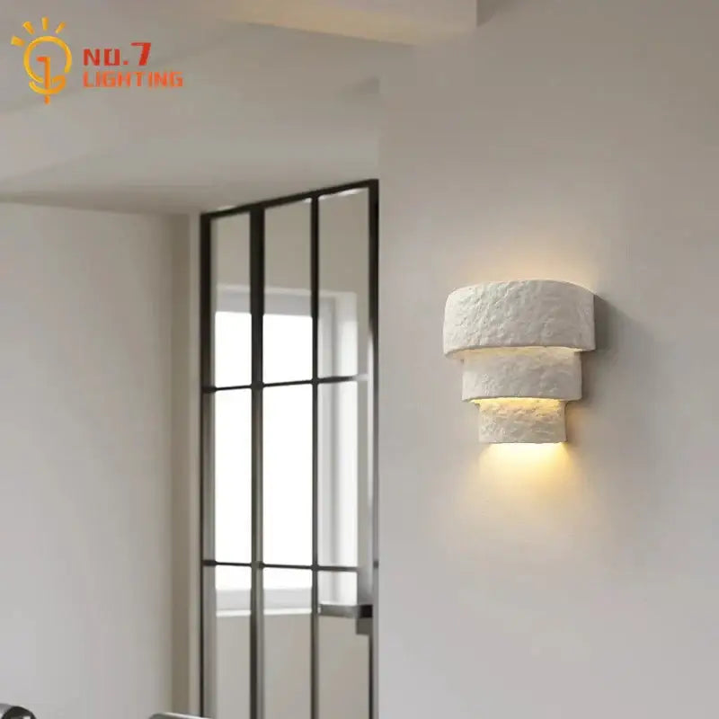 Minimalist bauhaus white gypsum wall lamp with textured layered design providing warm light for bedroom use