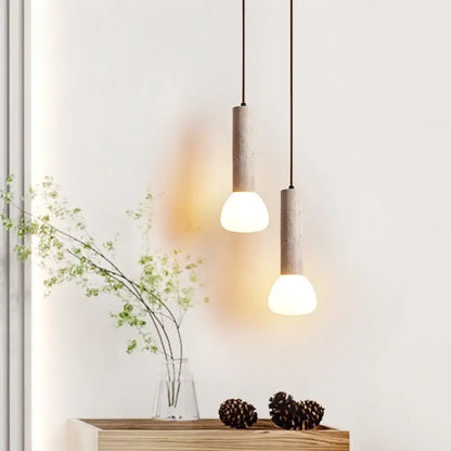Two minimalist beige concrete pendant lights with warm glass stone led shades for kitchen decorbites glass stone lighting