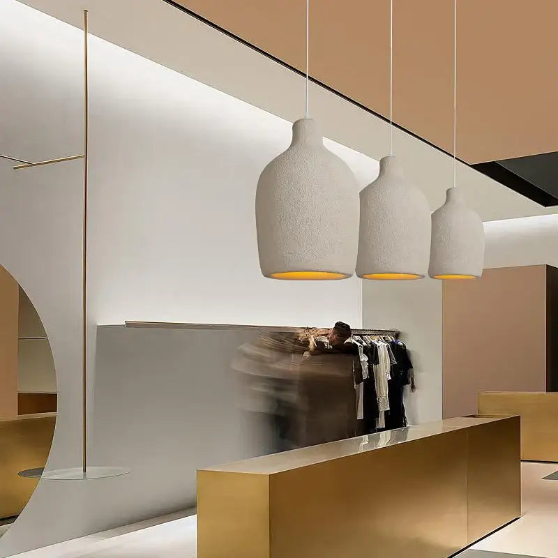 Minimalist beige cement chandelier light with three off-white ceramic pendant shades and warm yellow interiors for living room decorbites cement chandelier