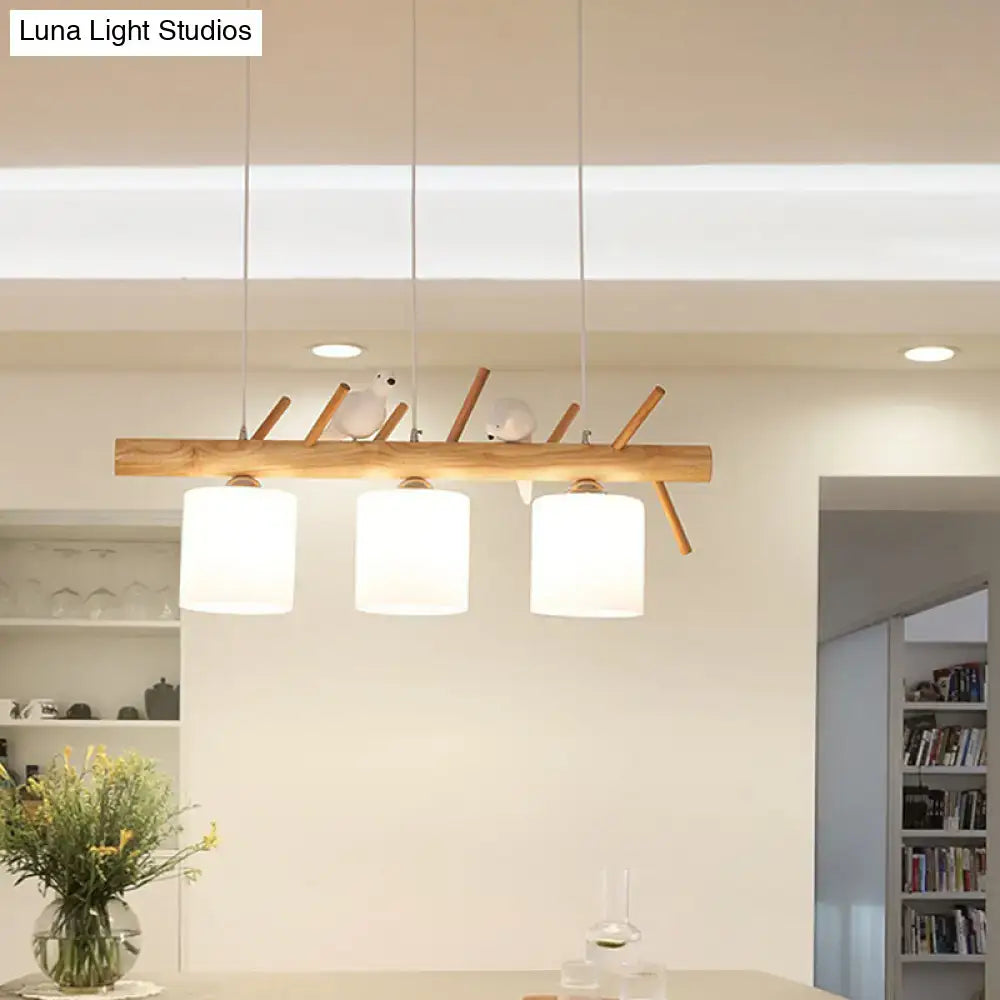 Modern wooden beige drum island lighting with three white glass shades and decorative bird on wood branch design