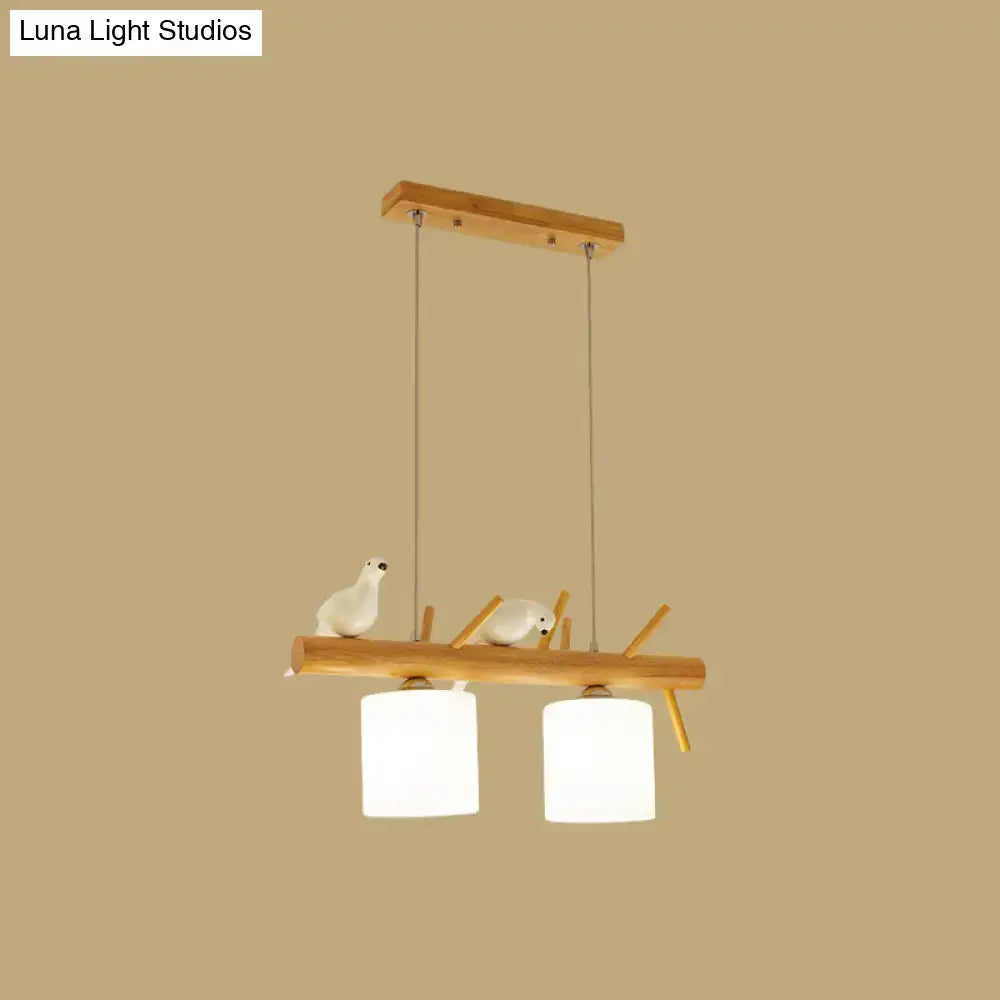 Minimalist beige drum island lighting with natural wood frame, white glass shades, and ceramic birds on wood branch design