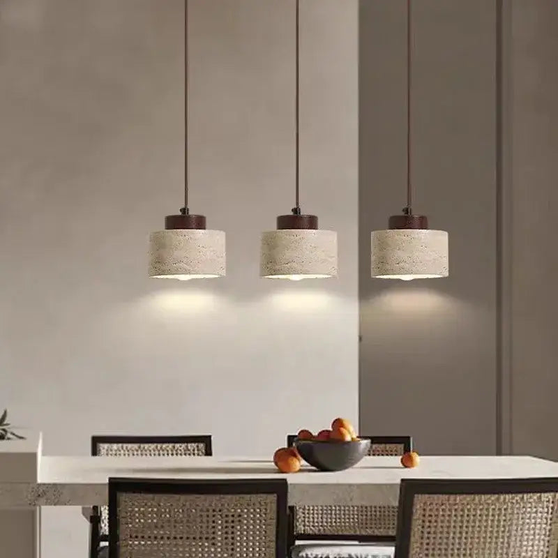 Three pendant lights with beige stone shade and dark brown fixtures hang above a dining table in kitchen dining room