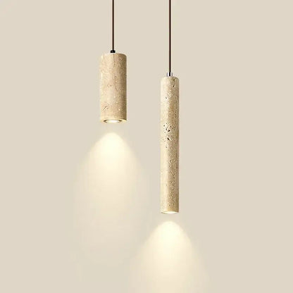 Two beige travertine cylindrical pendant lights with textured finish hang from black cords over dining table