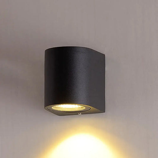 Minimalist black aluminum outdoor cylinder wall light with matte finish and warm focused light for outdoor space direct wired electric