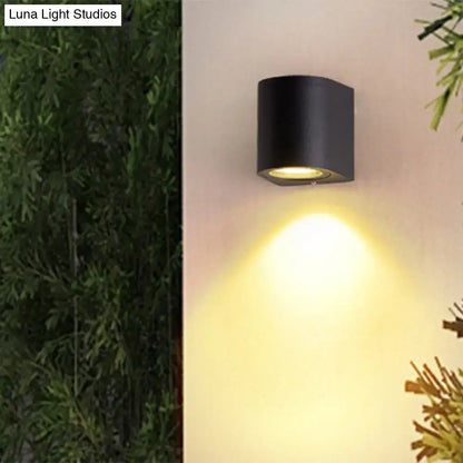 Minimalist black aluminum outdoor cylinder wall light with warm focused beam for direct wired electric outdoor space