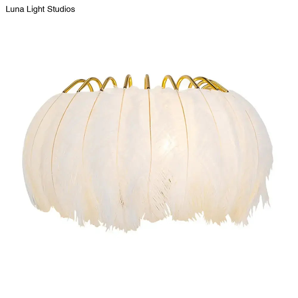 Minimalist black and gold feather wall sconce with off-white feather light type and golden metal fixture height for bedroom use