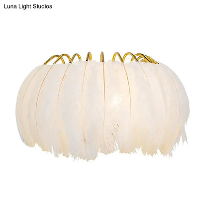 Minimalist black and gold feather wall sconce with off-white feather light type and golden metal fixture height for bedroom use