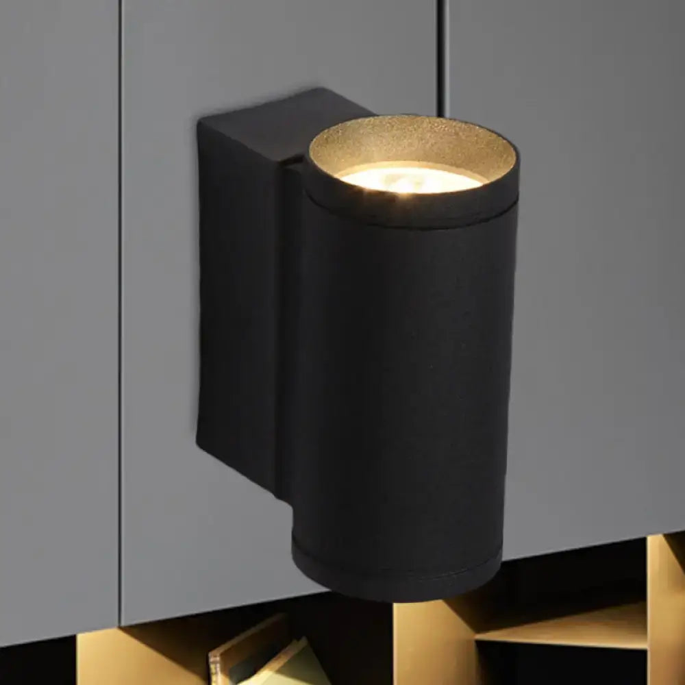 Minimalist black and gold metal wall mounted lamp with cylindrical design and warm focused illumination for bedrooms